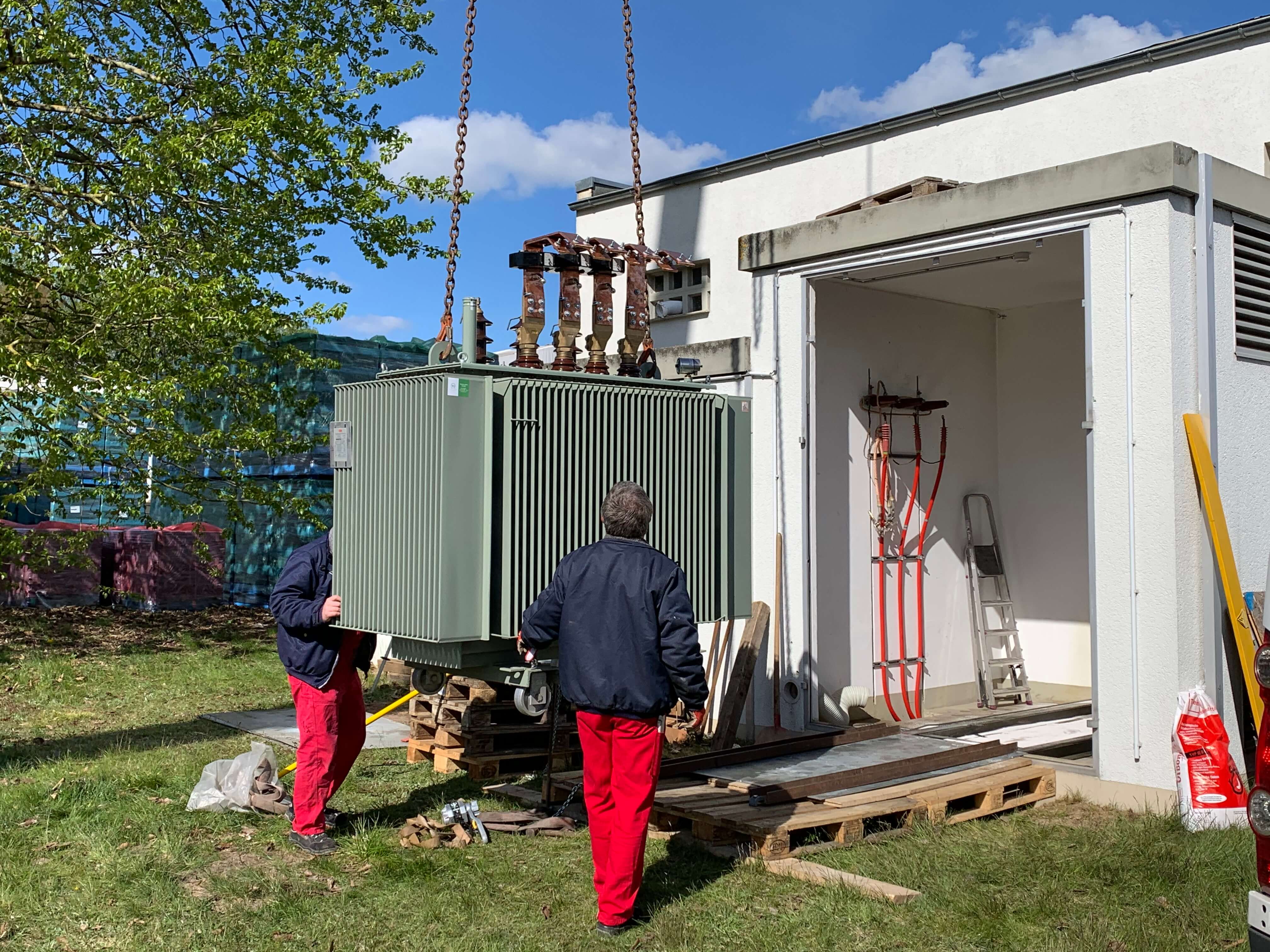Montage einer Trafostation vor einem Technikgebaeude