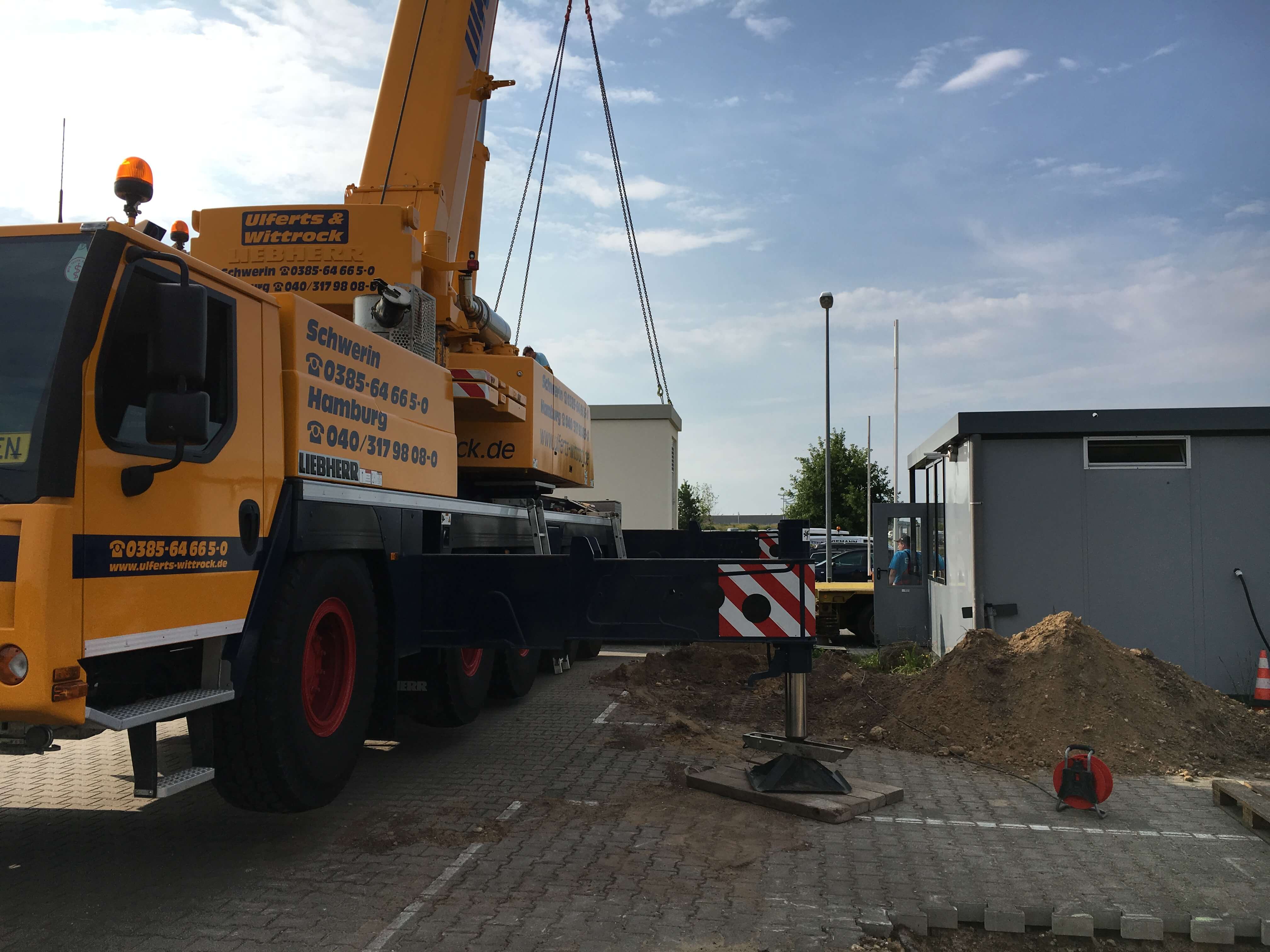 Kran hebt Trafostation auf einer Baustelle